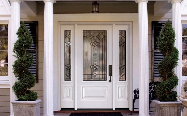 At Toronto Doors and Windows, you'll find a white front custom entry door installation complemented by columns and greenery on both sides.